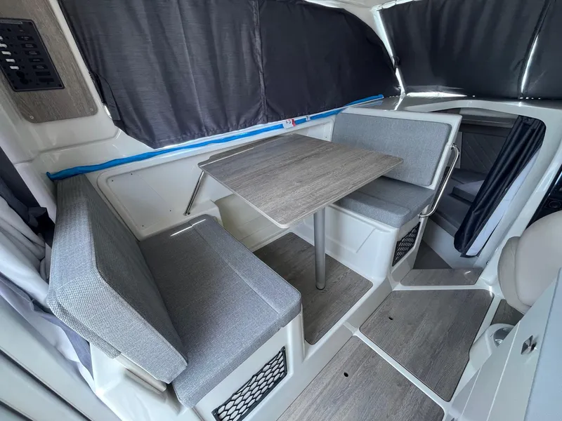 Slide: The Image of Interior of 2025 Bayliner Trophy T25 Explorer, featuring a compact dining area with gray seating. - 21