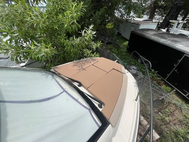 Slide: The Image of 2025 Bayliner Trophy T25 Explorer boat with tan deck cushions, surrounded by greenery. - 23