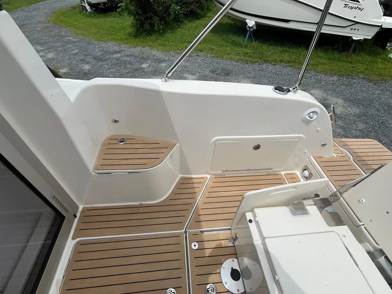 Slide: The Image of 2025 Bayliner Trophy T25 Explorer boat deck with wood finish and storage compartments. - 7