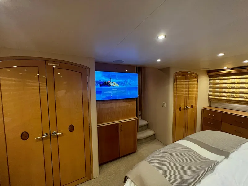Slide: The Image of Luxurious 2004 Hatteras 80 Motor Yacht bedroom with TV, wooden cabinetry, and ambient lighting. - 22