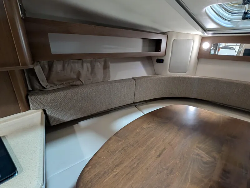Slide: The Image of Interior of 2015 Sea Ray 280 Sundancer with wood table and cushioned seating. - 12