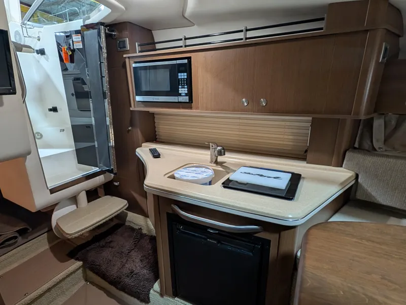 Slide: The Image of 2015 Sea Ray 280 Sundancer interior kitchen with microwave and compact fridge. - 13