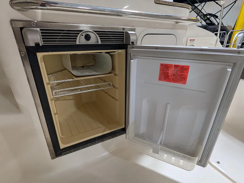 Slide: The Image of Open mini fridge on 2015 Sea Ray 280 Sundancer boat, showing interior shelves. - 26