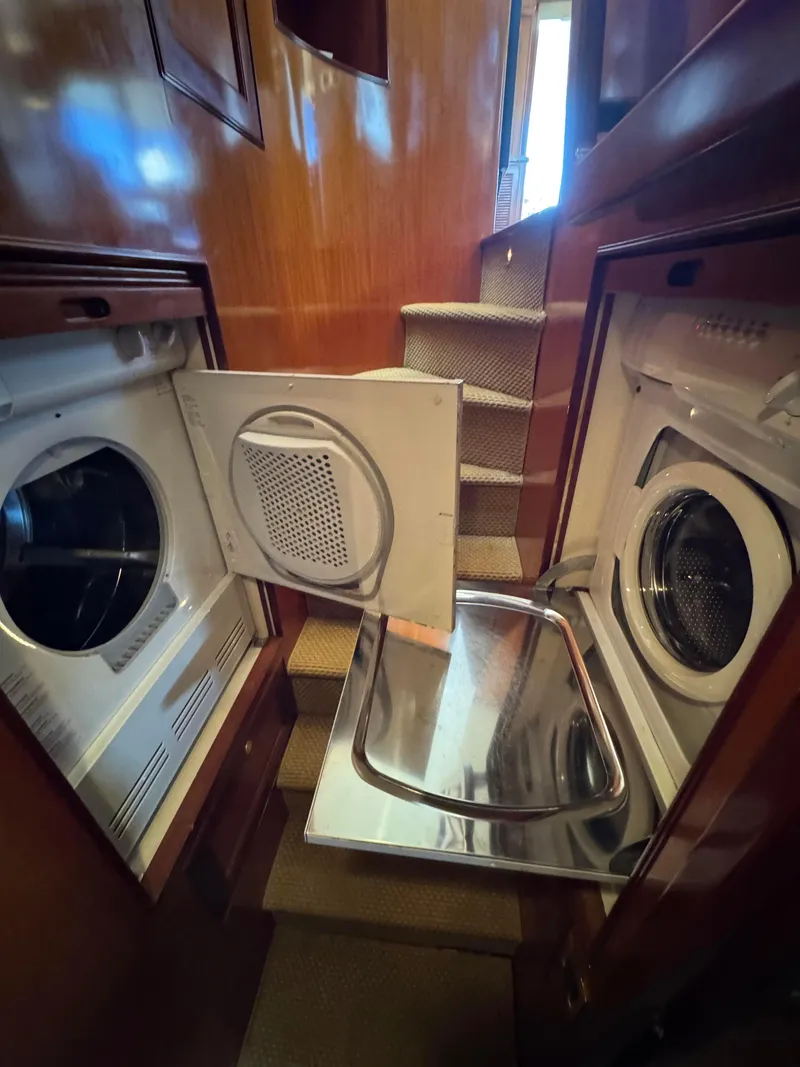 Slide: The Image of Laundry area inside a 2005 Offshore Yachts 72' model, featuring a washer and dryer. - 16