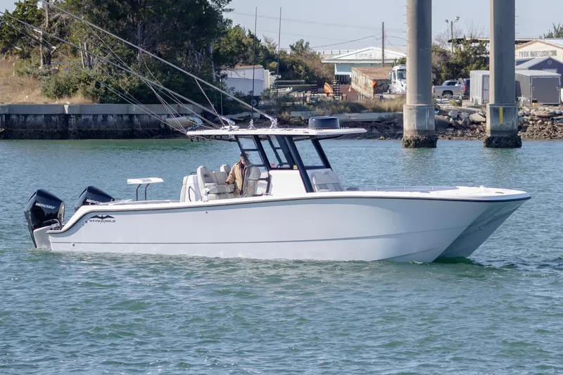 The Image of 2022 Invincible 33 Catamaran cruising on water near docks. - 1