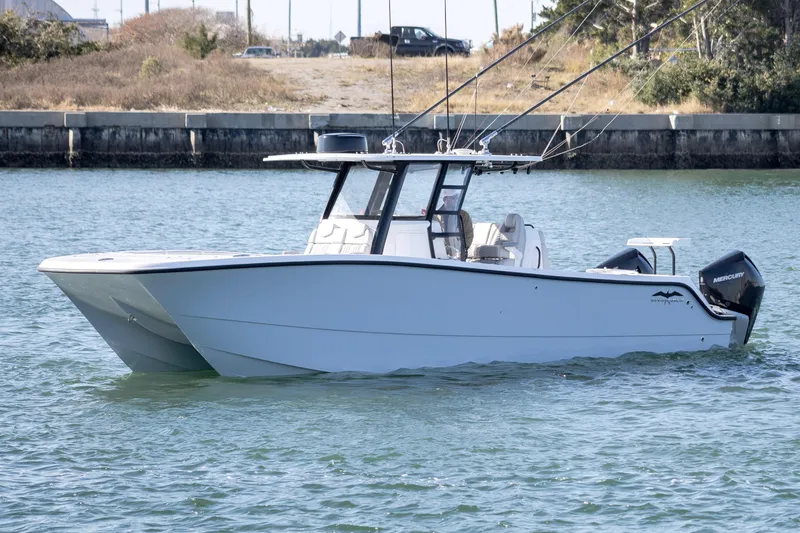 Slide: The Image of 2022 Invincible 33 Catamaran on water, featuring sleek design and fishing rods. - 3