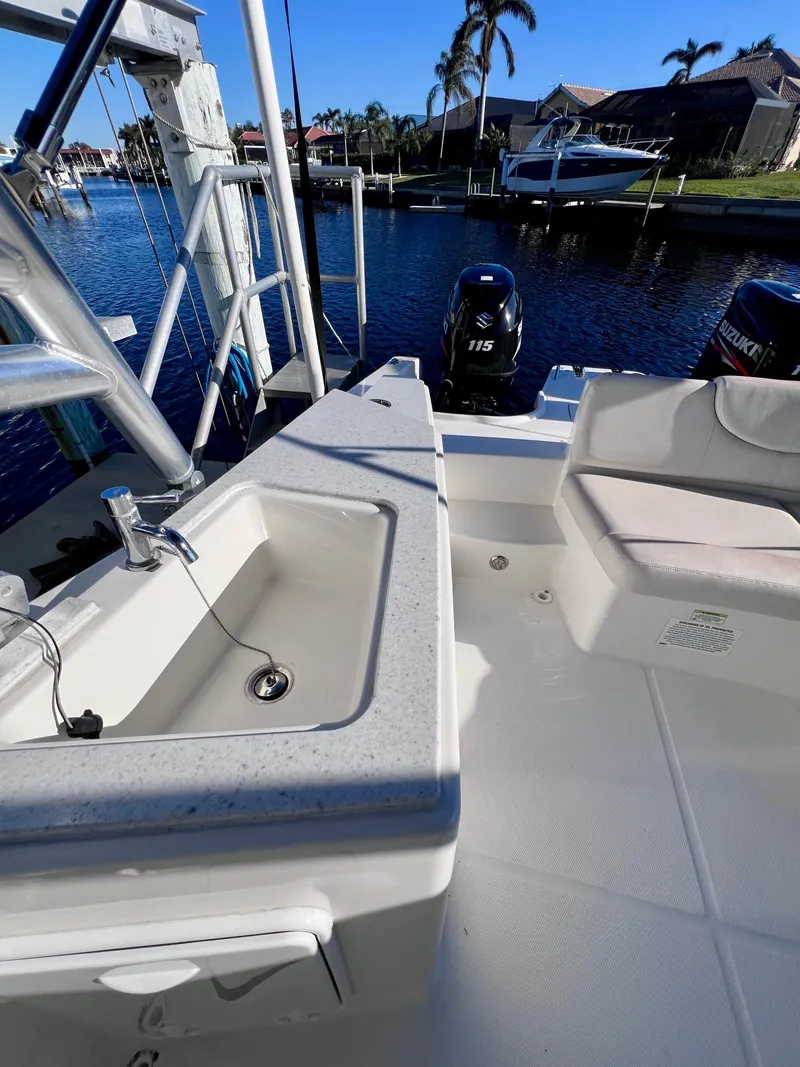 Slide: The Image of 2015 Carolina Cat 23 SD boat interior with sink and seating, docked by waterfront homes. - 13