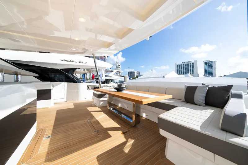 Slide: The Image of Luxurious Pearl 95 yacht deck with seating and table, 2025 model, city skyline in background. - 20