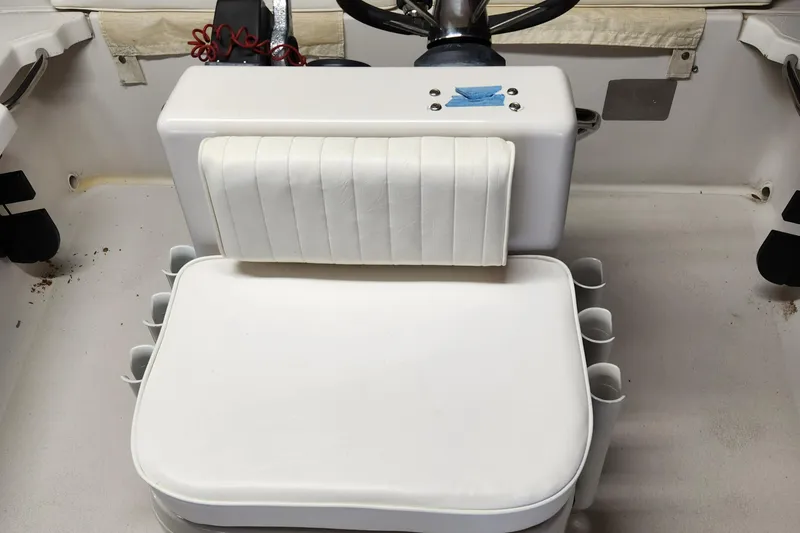 Slide: The Image of 1998 Hewes Bayfisher boat interior with white cushioned seating and steering console. - 7