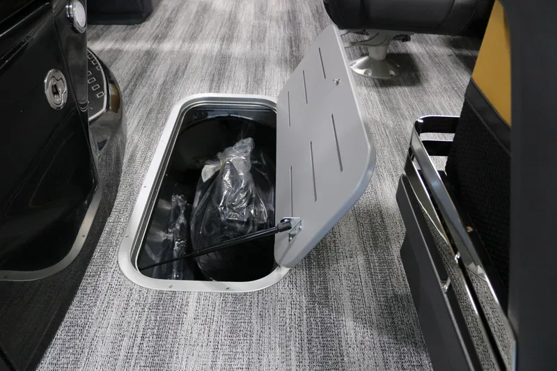 Slide: The Image of 2025 Bennington 22 M FASTBACK interior storage compartment with open hatch on carpeted floor. - 11