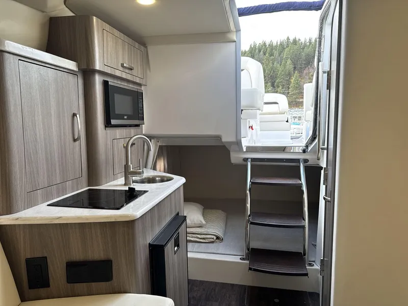 Slide: The Image of 2023 Regal 28EX boat interior with kitchenette, microwave, and stairs leading to deck. - 12