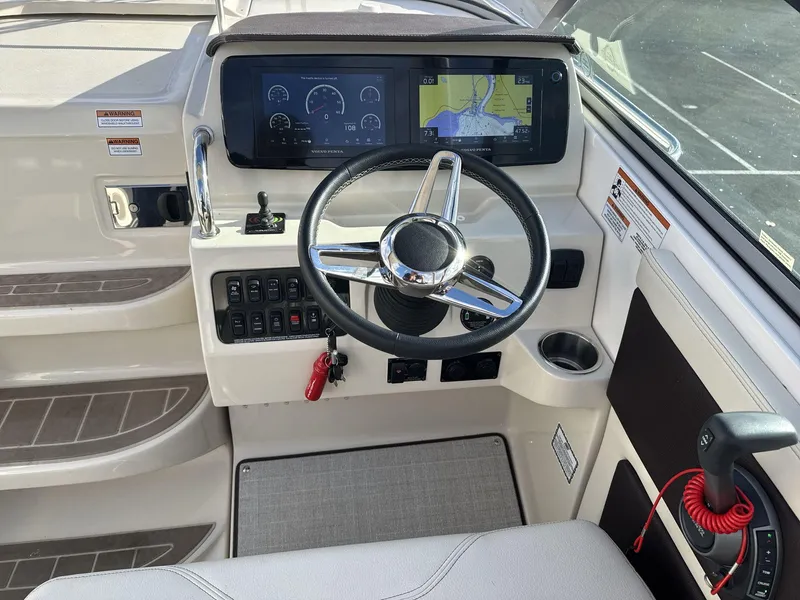 Slide: The Image of 2023 Regal 28EX boat helm with steering wheel, navigation display, and control panel. - 13