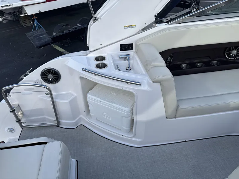 Slide: The Image of 2023 Regal 28EX boat interior with seating, cup holders, and cooler storage. - 16
