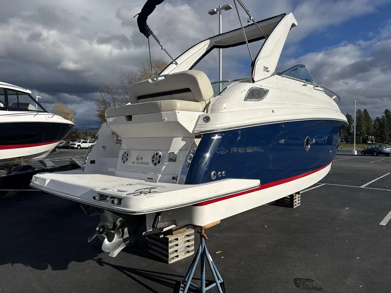 Slide: The Image of 2023 Regal 28EX boat on display in a parking lot under cloudy skies. - 7