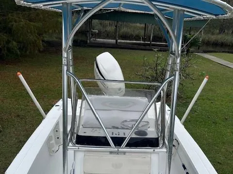 Slide: The Image of 2004 Triton 240 LTS boat with T-top and outboard motor, parked on grass. - 10
