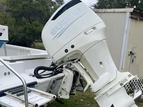 Slide: The Image of 2004 Triton 240 LTS boat with Suzuki outboard motor, parked outdoors. - 3