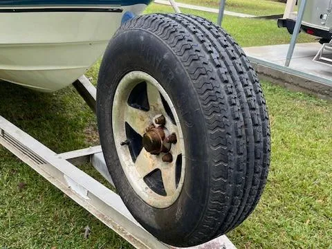 Slide: The Image of 2004 Triton 240 LTS boat trailer tire on grassy area. - 9