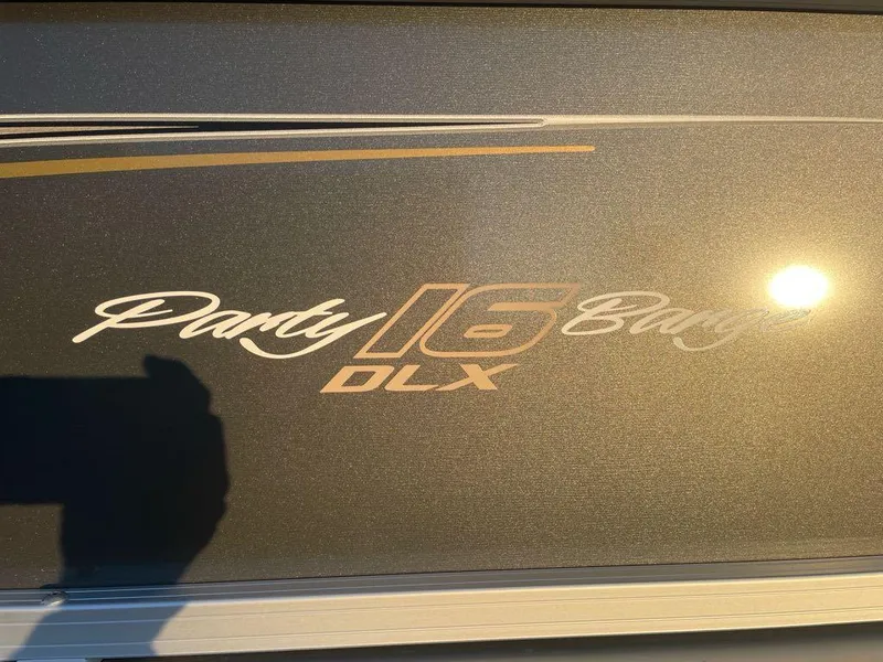 Slide: The Image of 2025 Sun Tracker Party Barge 16 DLX logo in sunlight. - 2