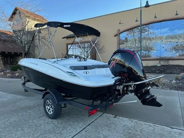 Slide: The Image of 2025 Tahoe T18 boat on trailer with outboard motor, parked outdoors. - 2