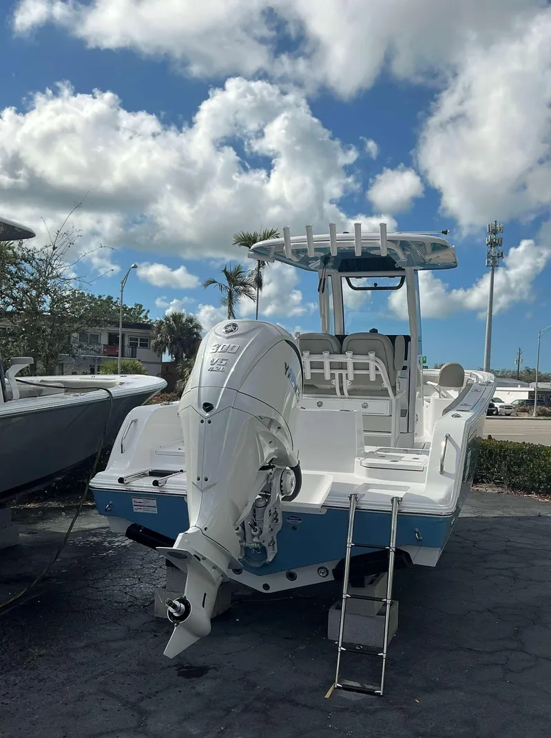 Slide: The Image of 2025 Sportsman 231 Heritage boat with outboard motor, parked under a cloudy sky. - 3