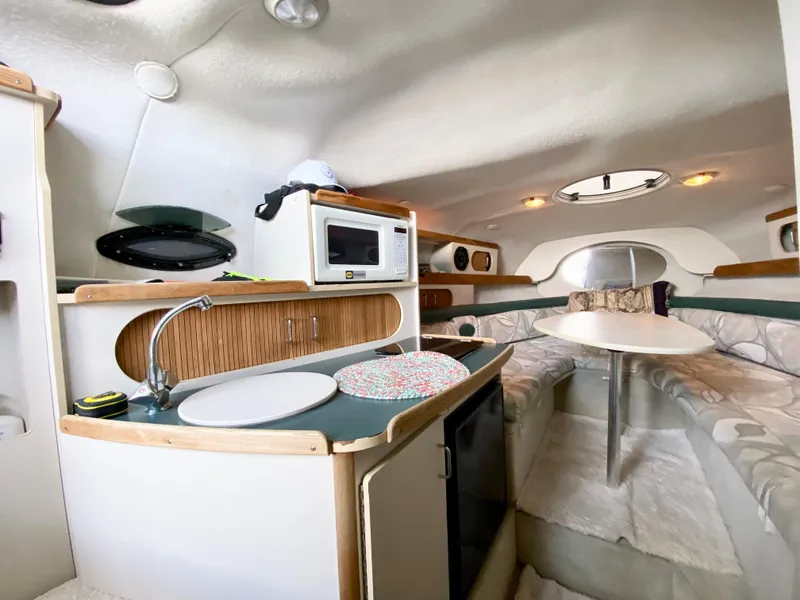 Slide: The Image of Interior of 1999 Four Winns 258 Vista boat with kitchenette and seating area. - 12