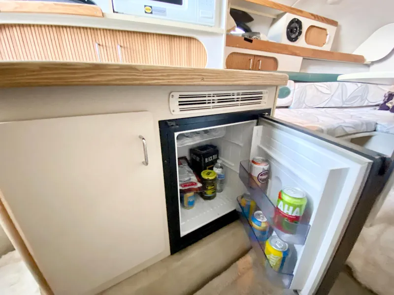Slide: The Image of 1999 Four Winns 258 Vista cabin interior with open mini fridge and beverages. - 17