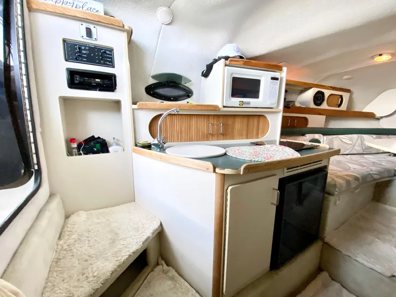 Slide: The Image of Interior of 1999 Four Winns 258 Vista boat with kitchenette and seating area. - 18