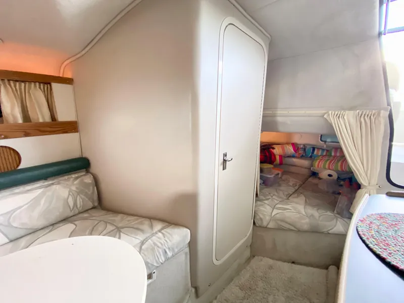Slide: The Image of 1999 Four Winns 258 Vista cabin interior with seating and cozy sleeping area. - 19