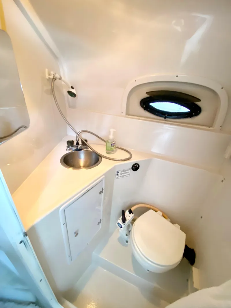 Slide: The Image of 1999 Four Winns 258 Vista boat bathroom with sink, toilet, and porthole window. - 21