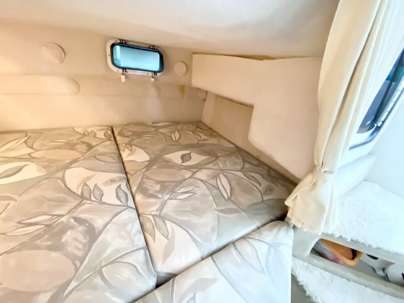 Slide: The Image of 1999 Four Winns 258 Vista cabin interior with floral-patterned bedding and small window. - 28