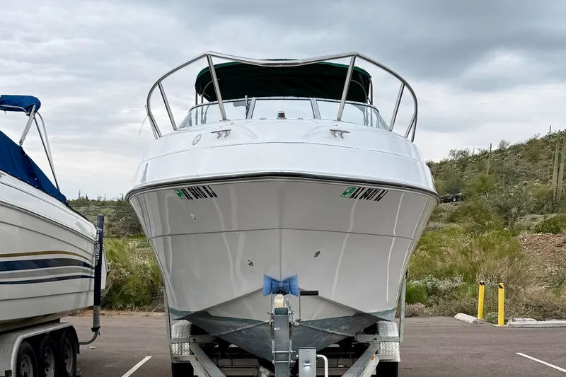 Slide: The Image of 1999 Four Winns 258 Vista boat on trailer, parked outdoors under cloudy sky. - 35