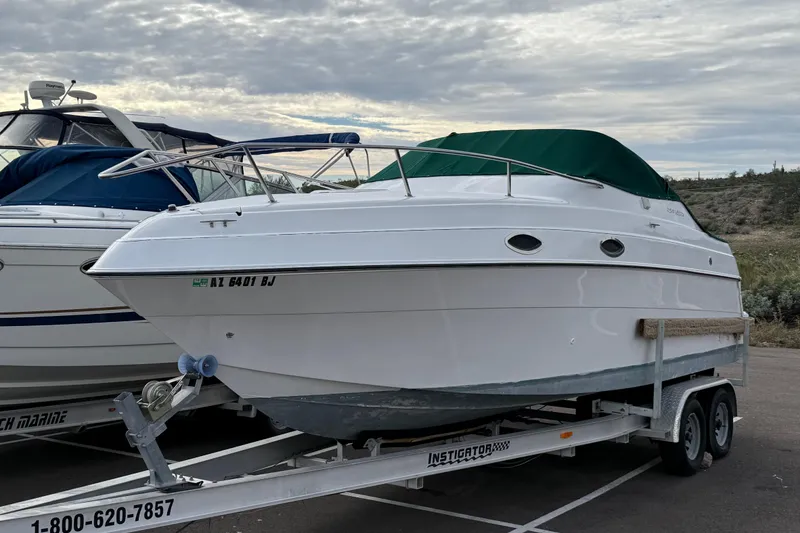 Slide: The Image of 1999 Four Winns 258 Vista boat on trailer, parked outdoors under cloudy sky. - 38