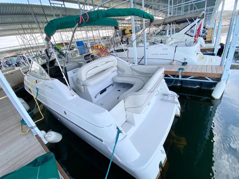 Slide: The Image of 1999 Four Winns 258 Vista boat docked in a marina, featuring white seating and green canopy. - 4