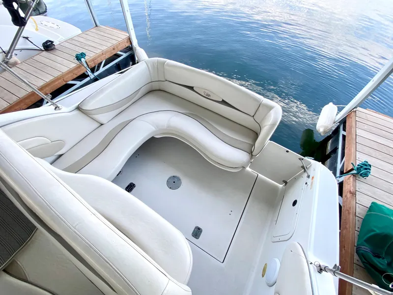 Slide: The Image of 1999 Four Winns 258 Vista boat interior with white seating, docked by calm water. - 9