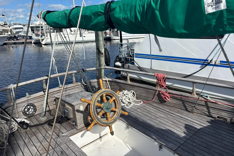 Slide: The Image of 1972 Fairweather Mariner 32 sailboat deck with wooden wheel and green sail cover. - 2