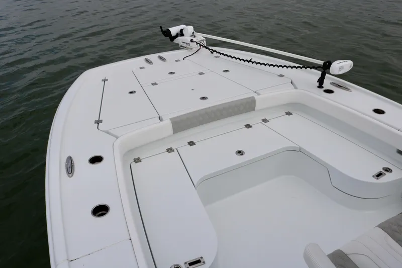 Slide: The Image of 2023 Freeman 28 boat deck with storage compartments and trolling motor on calm water. - 12