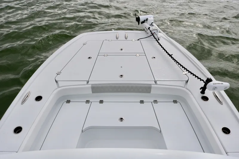 Slide: The Image of 2023 Freeman 28 boat deck with storage compartments and trolling motor on water. - 13