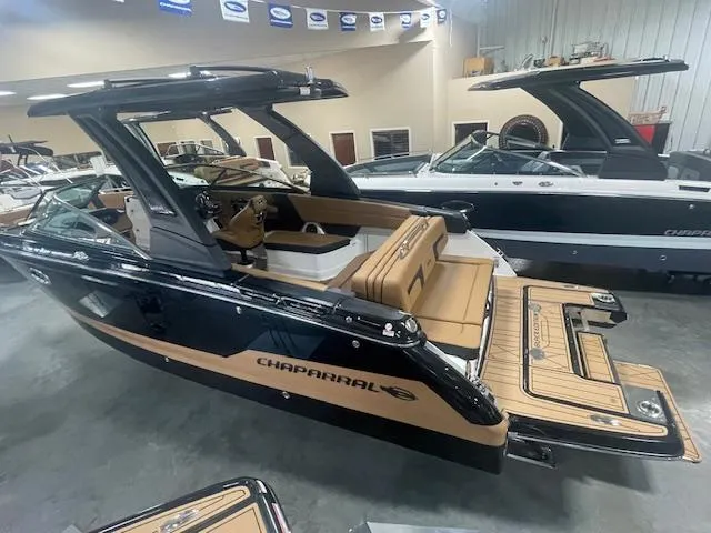 Slide: The Image of 2025 Chaparral 287 SSX boat in showroom, featuring sleek black and tan design. - 2