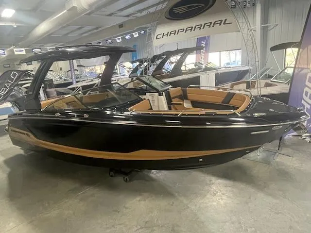 Slide: The Image of 2025 Chaparral 287 SSX boat in showroom, sleek black and tan design. - 3
