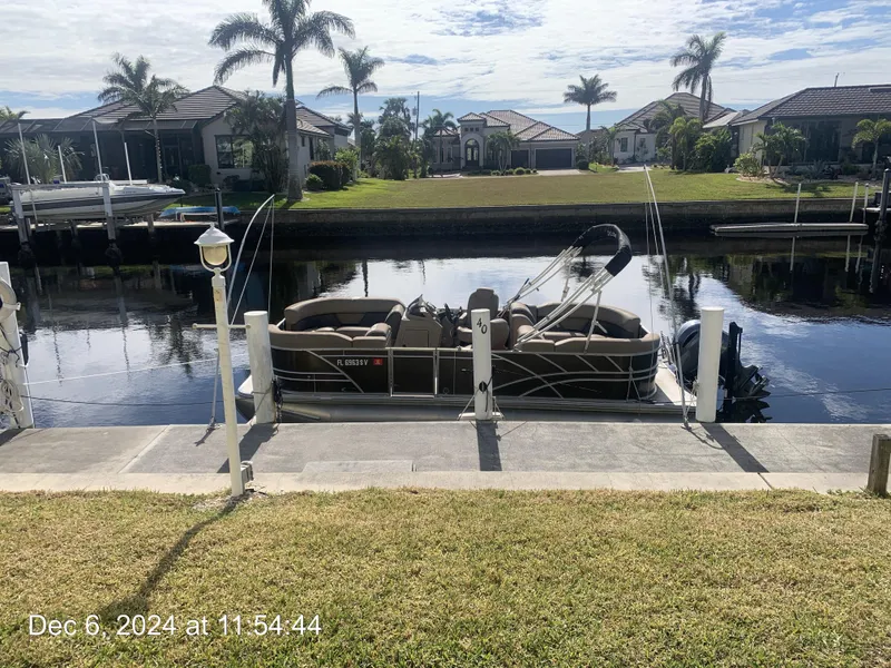 Slide: The Image of 2021 Sylvan Mirage 8522 LZ pontoon boat docked by a canal with palm trees. - 2