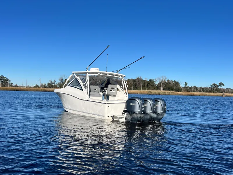 Slide: The Image of 2023 Albemarle 31 Dual Console boat on calm water with triple Yamaha engines. - 2