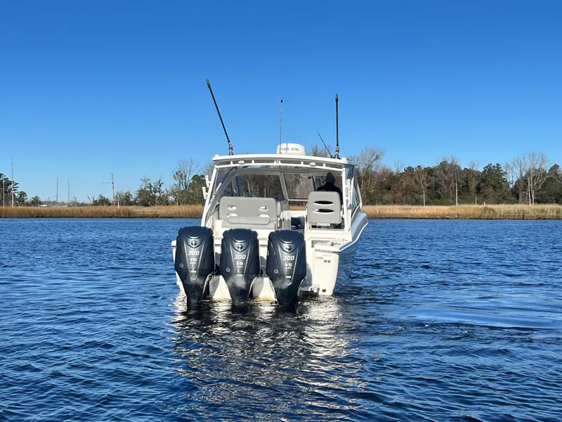 Slide: The Image of 2023 Albemarle 31 Dual Console boat with triple outboard engines on a calm lake. - 4