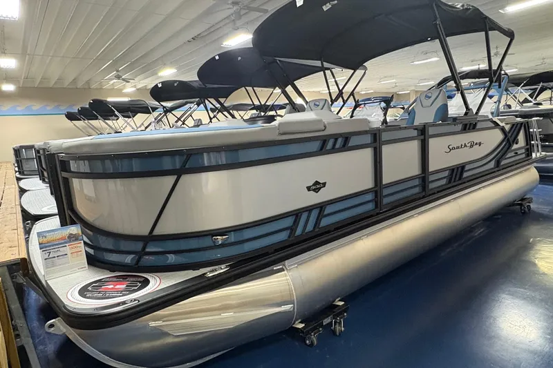 The Image of 2025 South Bay 500 pontoon boat displayed in showroom with sleek design and canopy. - 0