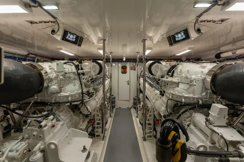 Slide: The Image of Engine room of 2018 Hatteras GT70 yacht, featuring dual engines and control panels. - 35