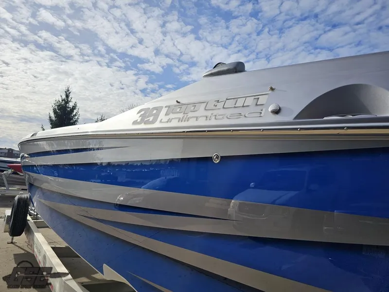 Slide: The Image of 2012 Cigarette 39' Top Gun Unlimited boat with blue and silver detailing under a cloudy sky. - 24