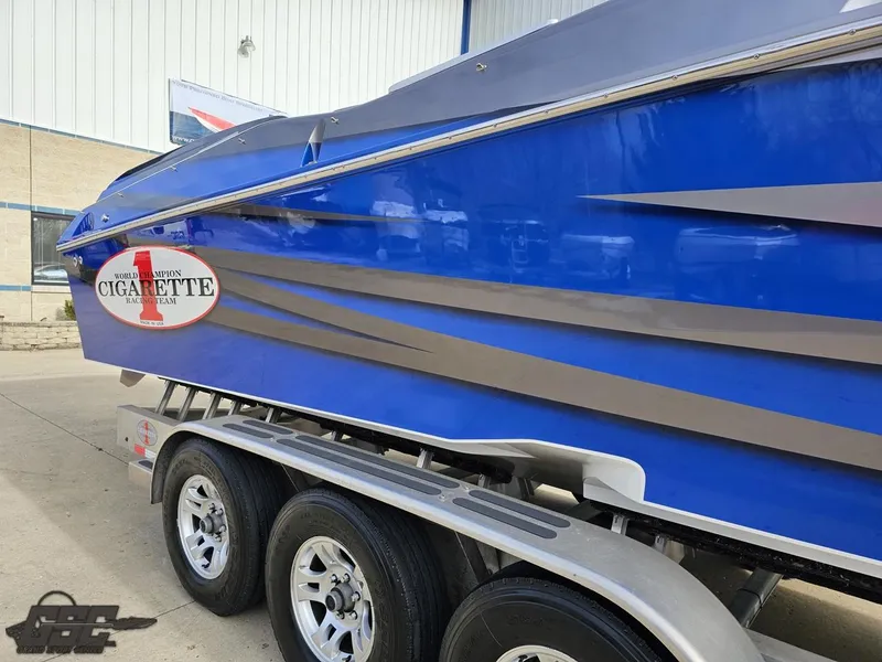 Slide: The Image of 2012 Cigarette 39' Top Gun Unlimited boat in vibrant blue on a trailer. - 8