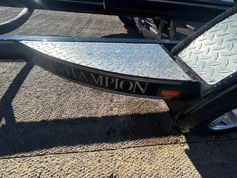 Slide: The Image of 2009 Champion 210 Elite boat with sleek design, parked outdoors under clear blue sky. - 36