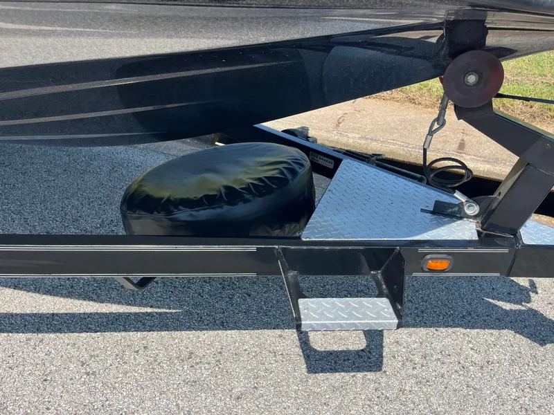 Slide: The Image of 2009 Champion 210 Elite boat trailer near water, empty, with other boats in background. - 46