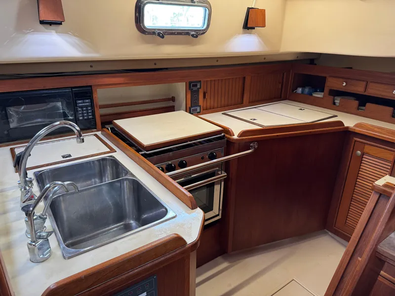 Slide: The Image of 1999 Island Packet 45 yacht kitchen with sink, stove, and wooden cabinetry. - 21