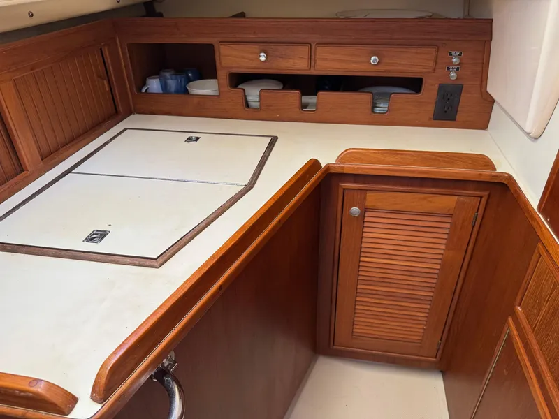 Slide: The Image of 1999 Island Packet 45 yacht kitchen with wooden cabinetry and white countertops. - 22
